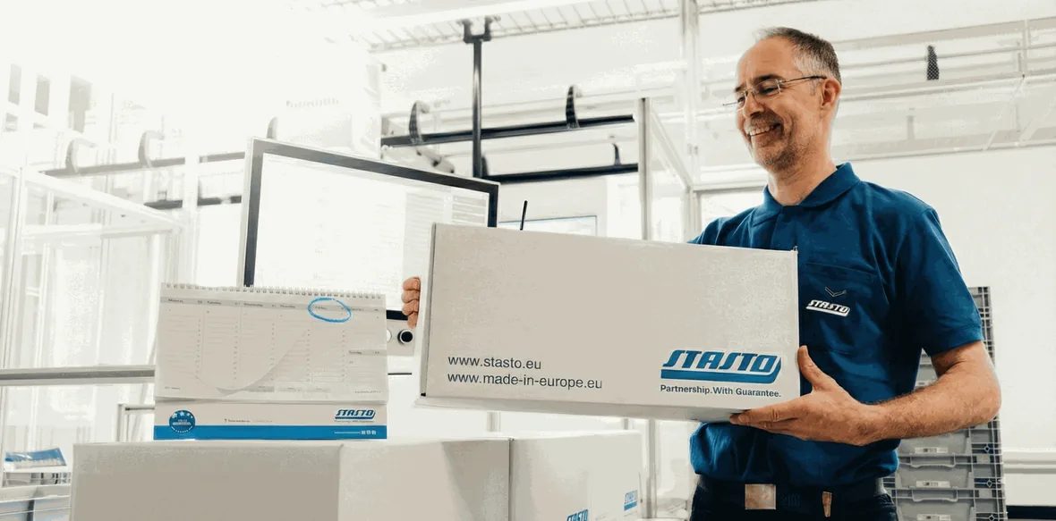 STASTO Mitarbeiter mit versandfertigem Paket vor dem Terminkalender